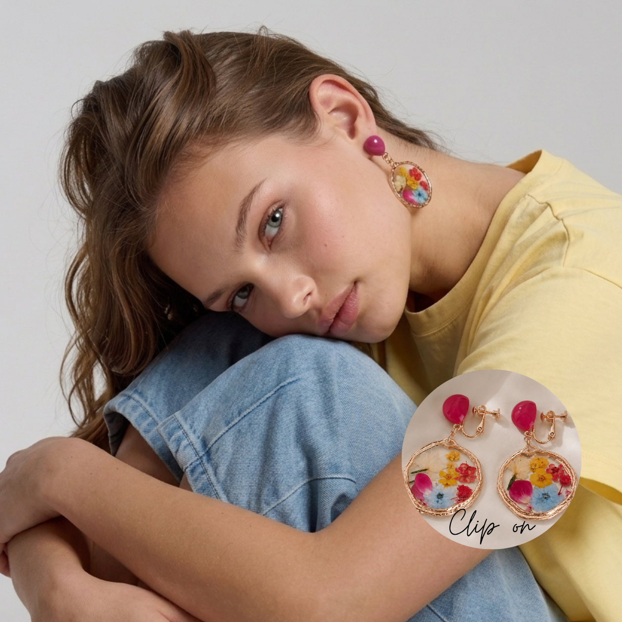 Image of A woman wearing colorful floral clip-on earrings with pink tops and round gold-toned bottoms, shown in a close-up lifestyle shot with a circular inset detail of the earrings.