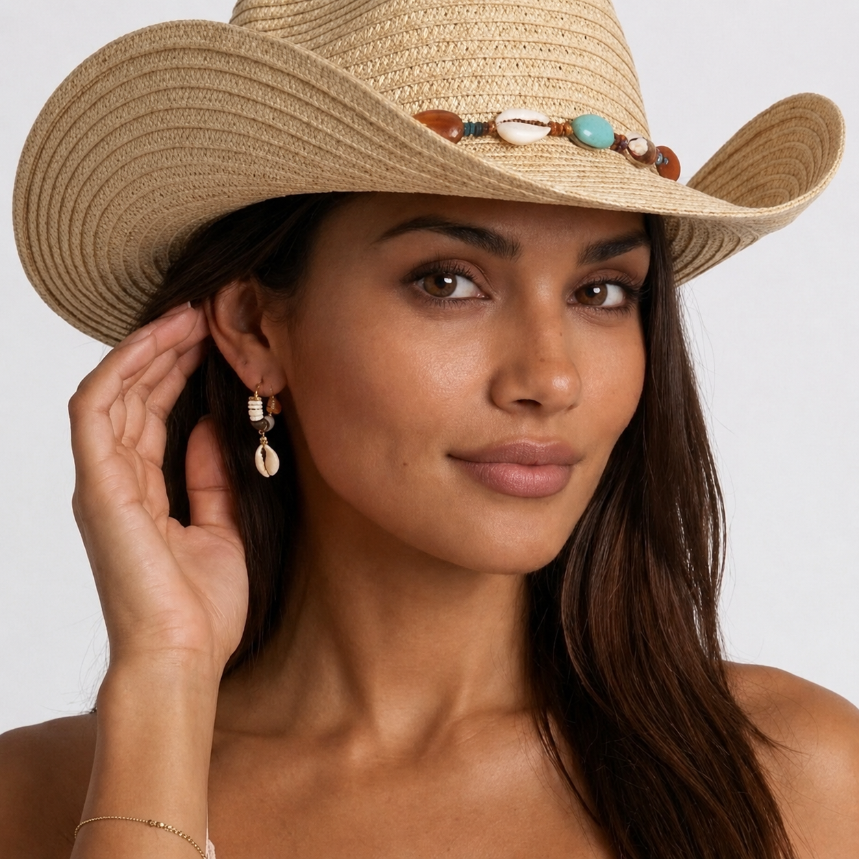 Image of Woman wearing seashell earrings with a straw hat, close-up portrait