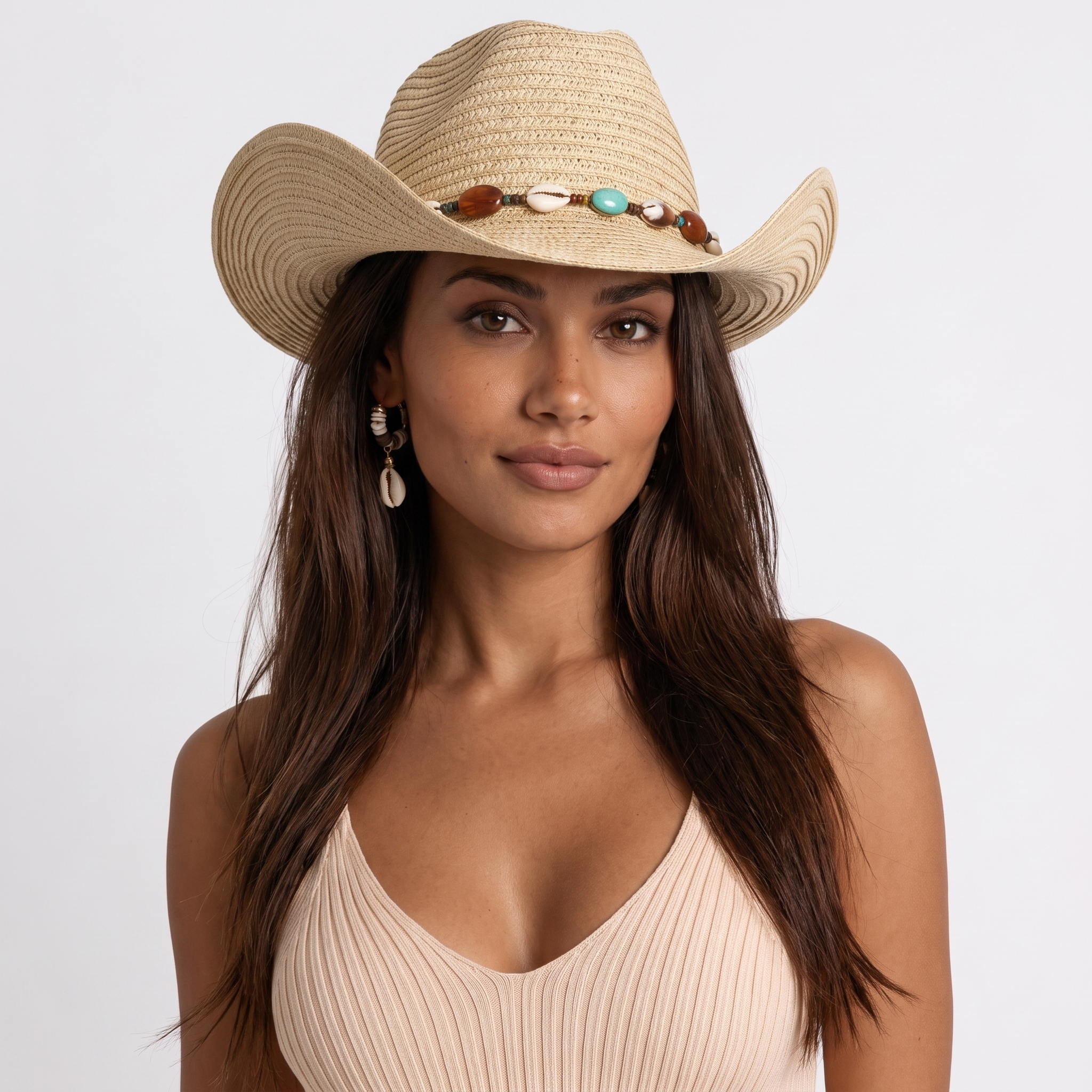 Image of Woman wearing a coastal cowgirl hat in raffia straw with turquoise, wood, and cowrie shell trim, close-up portrait