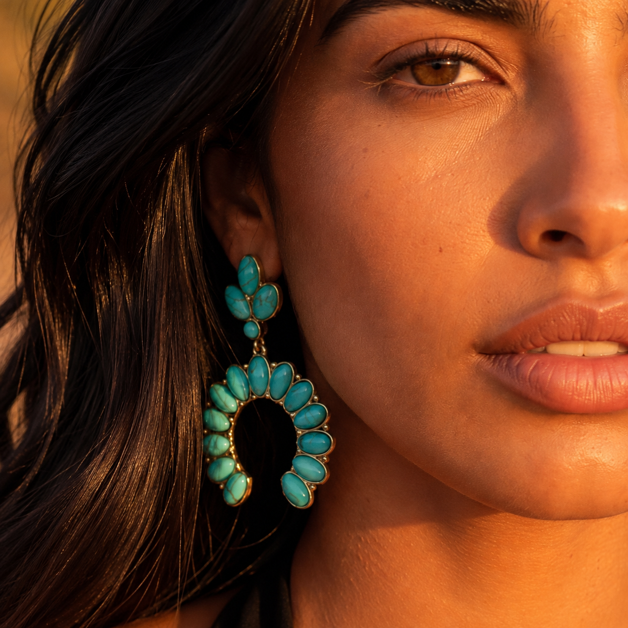 Image of A close-up of a woman's face and ear wearing a large turquoise and gold statement earring, with warm golden-hour sunlight highlighting her features and the jewelry.