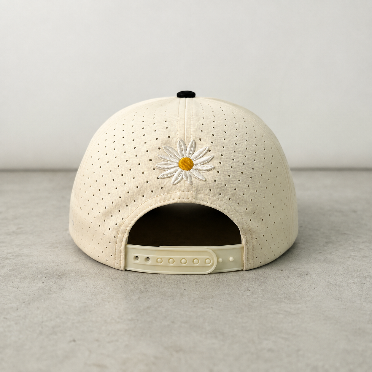 Image of Back view of a vintage trucker hat on a neutral background, showing the embroidered daisy detail and adjustable snapback closure