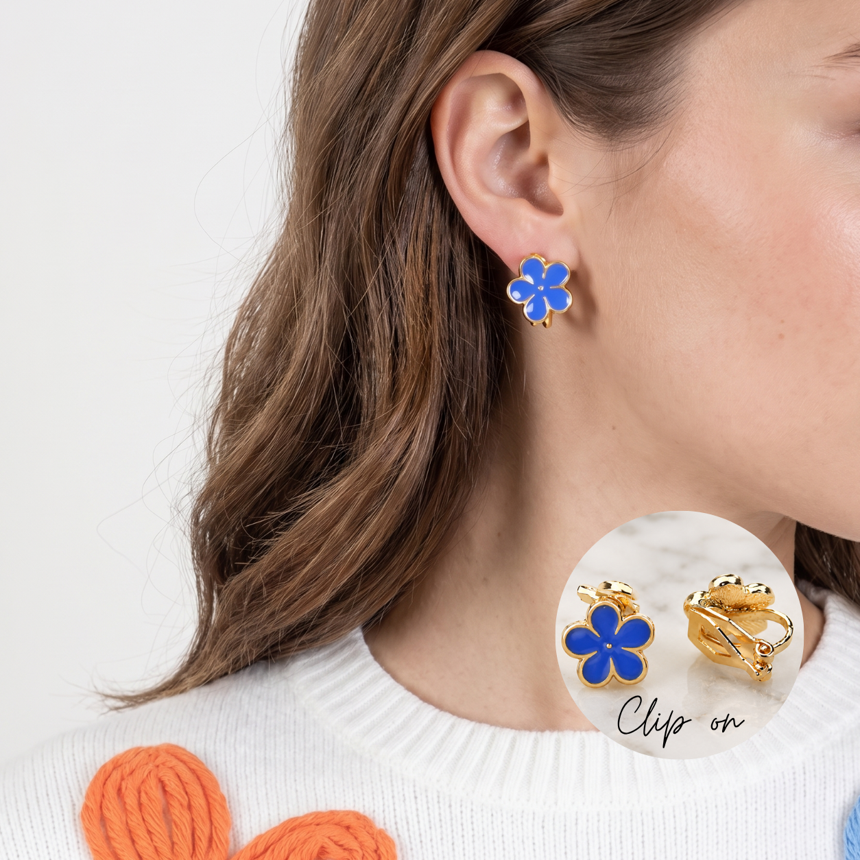 Image of A close-up of a woman wearing a gold and blue flower-shaped clip-on earring, with a circular inset showing the back of the earring and the text 'Clip on'.