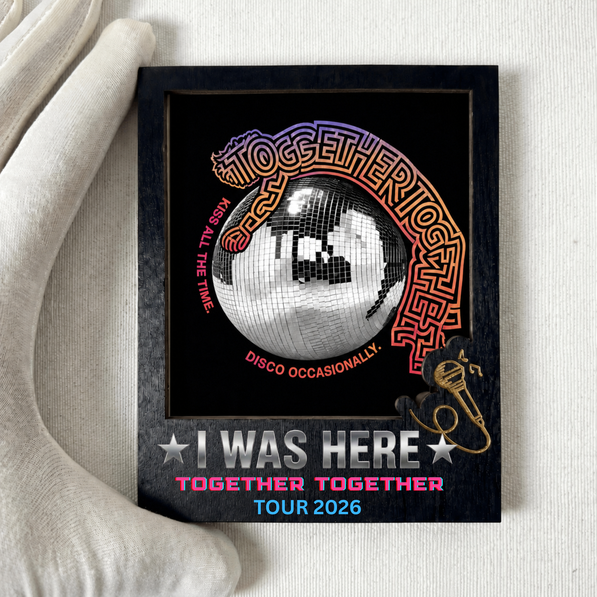 Image of A framed concert commemorative plaque for KISS's 'Together Together' tour 2026, held by a white gloved hand. The black plaque features a central silver and black disco ball graphic, stylized KISS lettering, and text reading 'I WAS HERE TOGETHER TOGETHER TOUR 2026'.