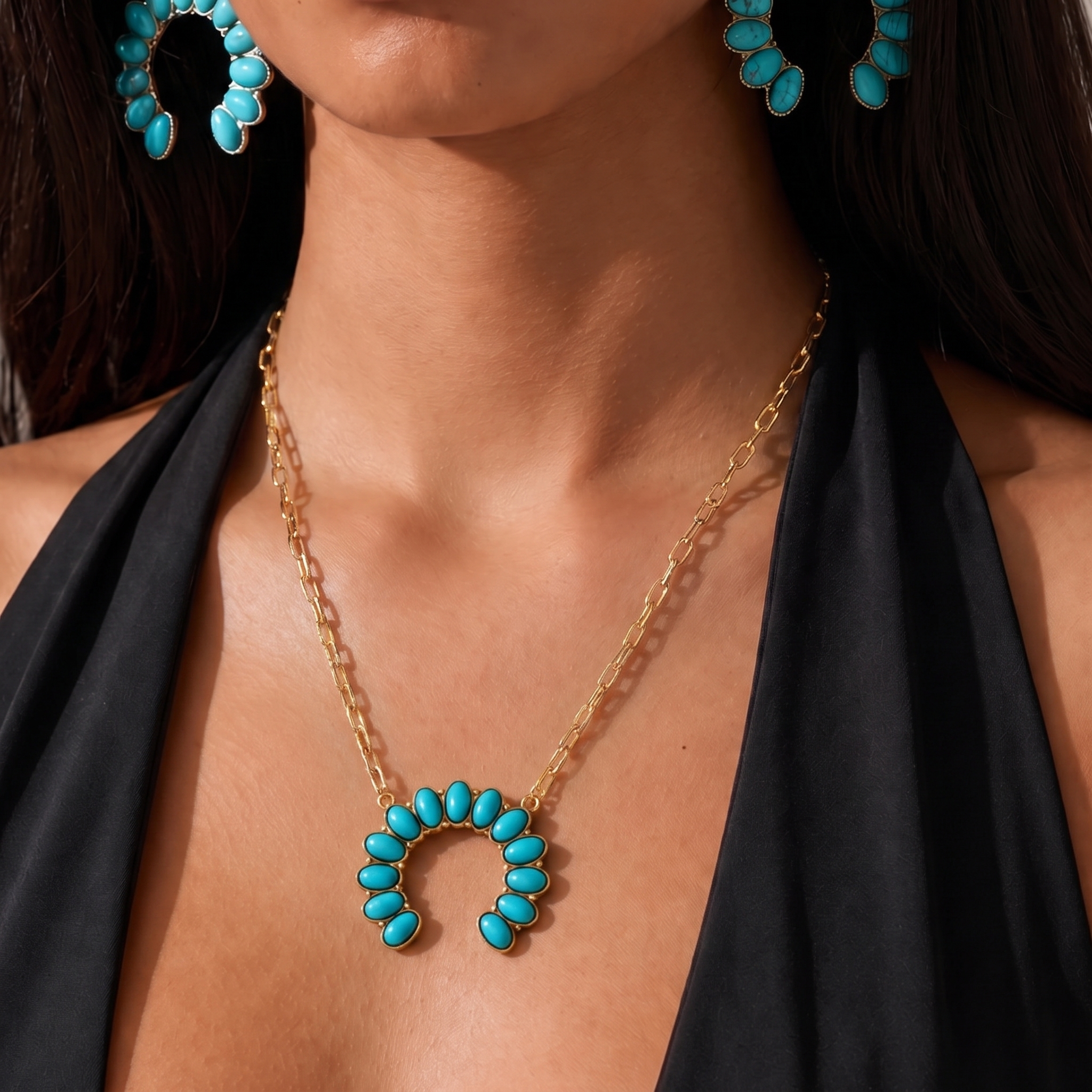 Image of A gold chain necklace with a crescent-shaped turquoise stone pendant, worn by a model in a black halter top. Matching turquoise and gold hoop earrings are partially visible.