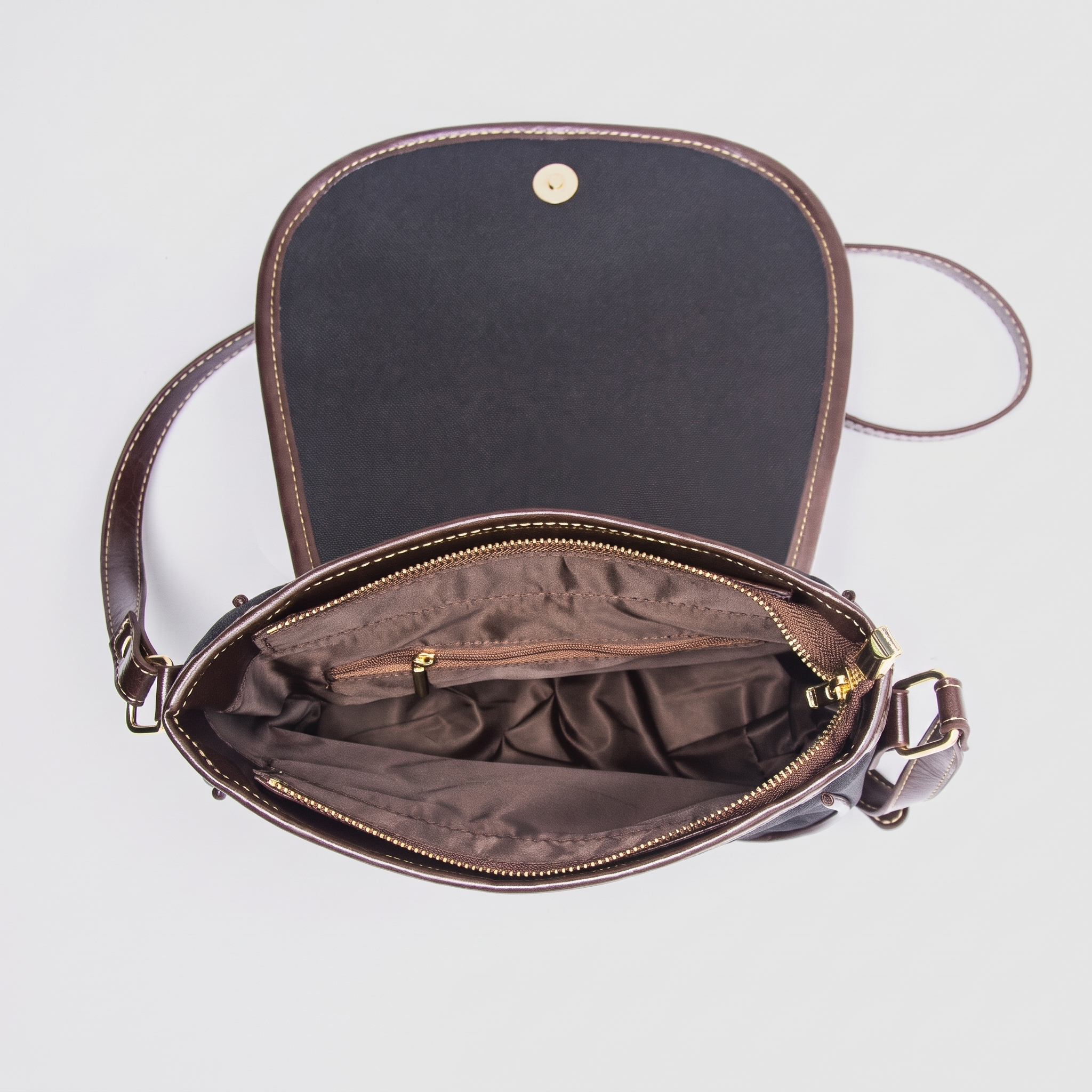 Image of Inside a piano key crossbody bag, showing the zip-top main compartment, interior zip pocket, and magnetic snap flap