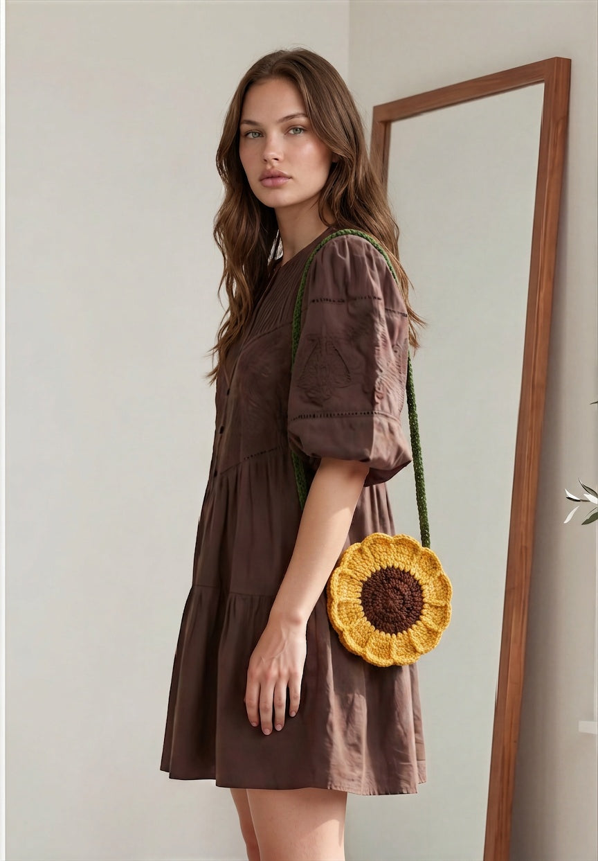 Image of A woman wearing a fall crocheted sunflower-shaped shoulder bag with a green strap.