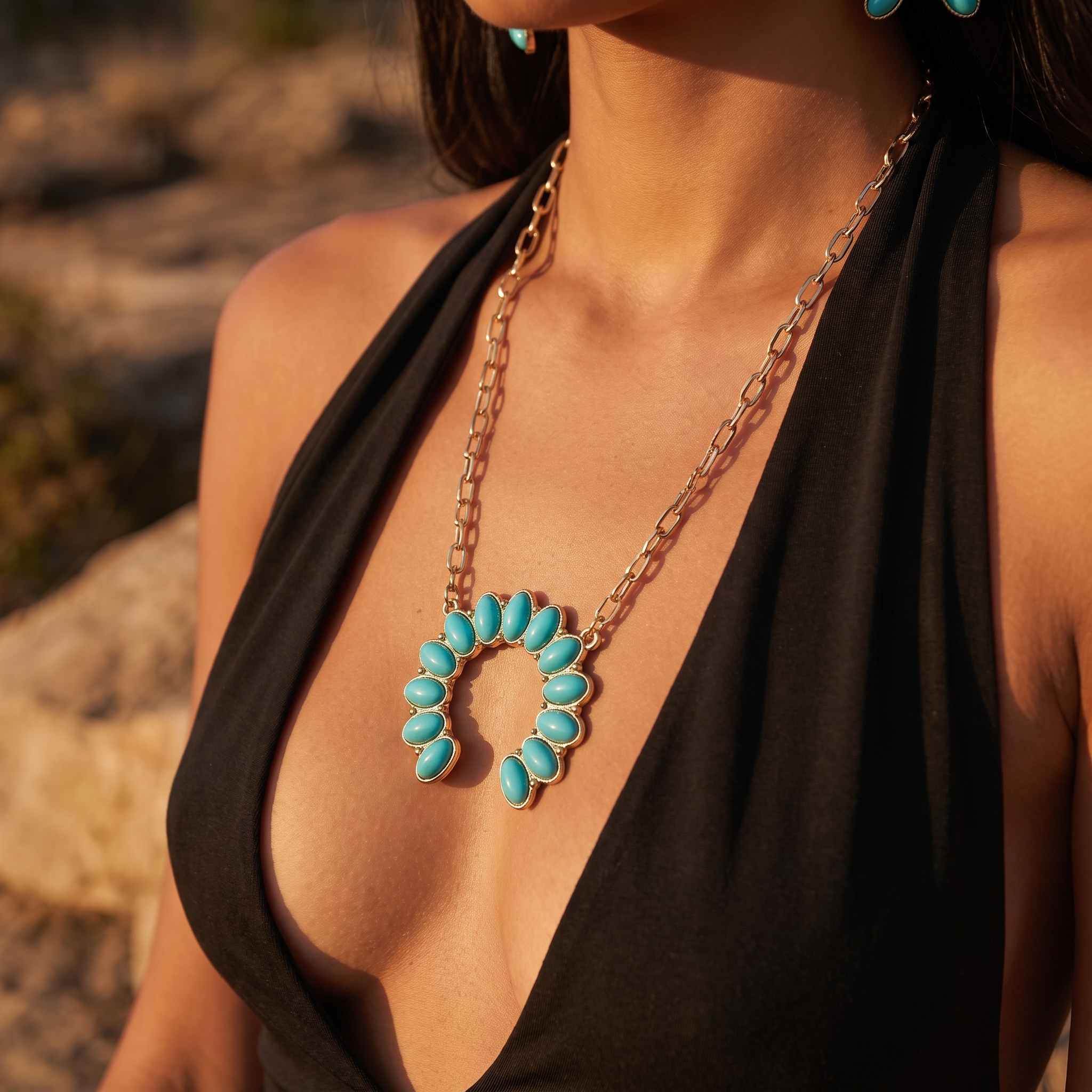 Image of A close-up lifestyle shot of a woman wearing a Western Turquoise Necklace, paired with a black halter top against a warm, rocky outdoor background.